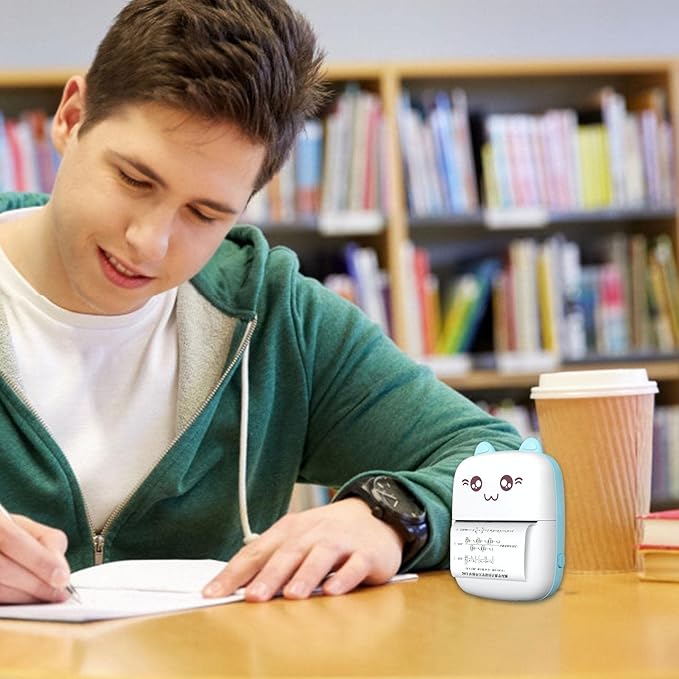 Person studying with a Inkless Mini Printer on a table in a library setting